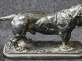 statue of a dog standing on a silver plate on a black background