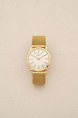 a close up of a gold watch on a white surface
