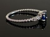 an engagement ring with a blue sapphire and diamonds on a black surface