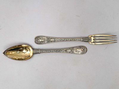 une paire de cuillères et une fourchette en métal argenté posées sur un fond blanc
