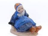 une figurine représentant une femme assise sur un rocher