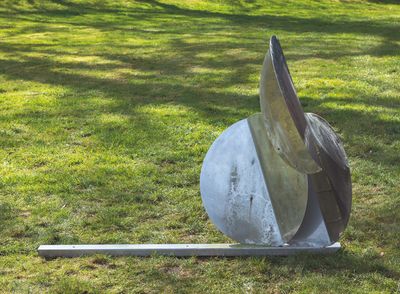 une sculpture métallique posée à même le sol, dans l'herbe