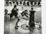 a black and white photo of two children playing with a fire hydrant