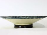 a blue and white bowl sitting on a black stand