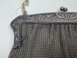 a metal purse hanging on a wall with a chain around it