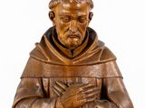 an old wooden statue of a man holding a book