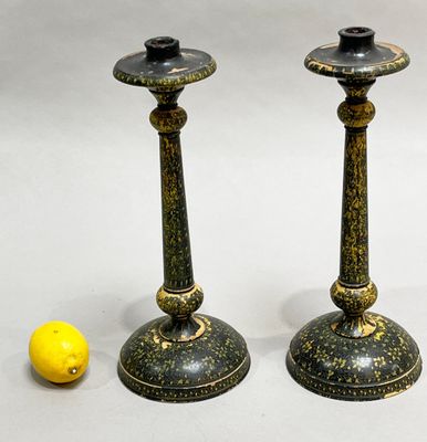 pair of black and gold candlesticks with a lemon next to them