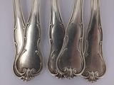 four silverware spoons with ornate designs on them sitting on a table
