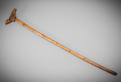 an old wooden stick with a carved handle on a gray background