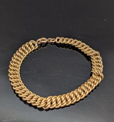 gros plan d'un bracelet en chaîne en or sur une table
