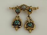 paire de boucles d'oreilles dorées ornées de pierres turquoise sur fond blanc