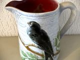 un pichet en céramique orné d'un oiseau, posé sur une table