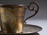 a silver cup and saucer sitting on a plate