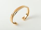 a close up of a gold cuff bracelet on a white background