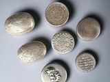 six pièces d'argent sont disposées en cercle sur une surface blanche