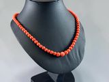 a black mannequin with a red beaded necklace on it
