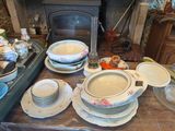 many plates and bowls sitting on a table with a fireplace in the background