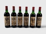 quatre bouteilles de vin sont alignées sur une surface blanche