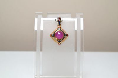 purple stone pendant on display in clear acrylic display case