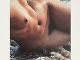 a picture of a man laying on the beach in the water