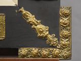 a black and gold chest of drawers with a clock on it