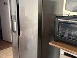 un réfrigérateur argenté dans une cuisine où se trouve un micro-ondes posé sur le plan de travail