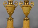 une paire de vases anciens en laiton sur socles, sur fond gris