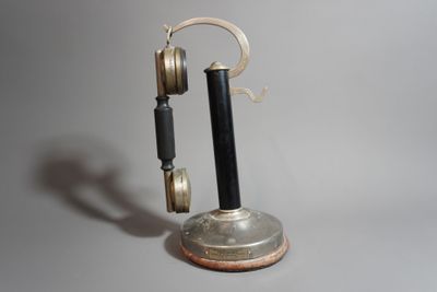 un objet argenté et noir posé sur un socle, sur une surface grise