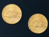two gold coins sitting on top of a black surface next to each other