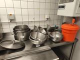 de nombreuses casseroles et poêles posées sur un plan de travail en inox