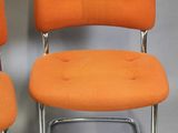 pair of orange chairs with chrome legs on a white background