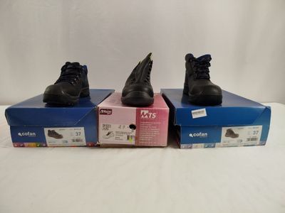 two pairs of black shoes sitting on top of boxes on a white surface