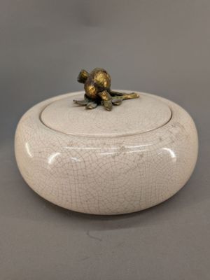 un petit bol blanc orné d'une grenouille dorée