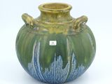 a green and blue vase with a tag on it