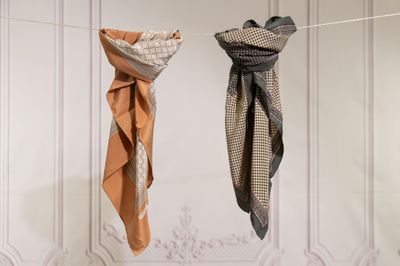 two scarfs hanging on a clothes line in front of a white wall