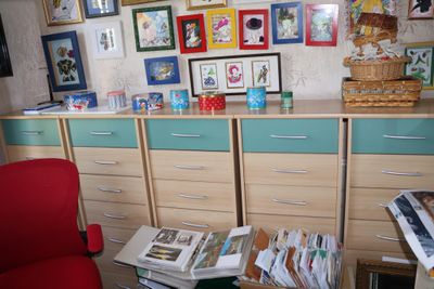 a red chair sitting in front of a desk in a room with pictures on the wall
