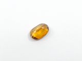 a close up of a yellow sapphire stone on a white surface