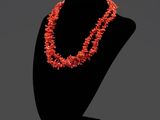 un collier composé de perles de corail, présenté sur un mannequin noir