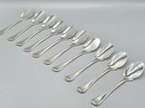 six silver spoons are lined up in a row on a white surface