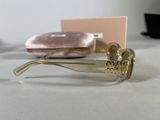 sunglasses with a gold frame and a pink case on a table