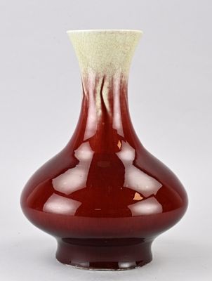 un vase rouge avec un couvercle blanc posé sur une table