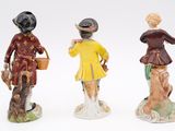 three figurines of people dressed in different outfits and hats
