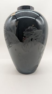un vase noir orné d'un dragon sur fond blanc