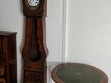 une horloge de parquet posée à côté d'une petite table dans une pièce