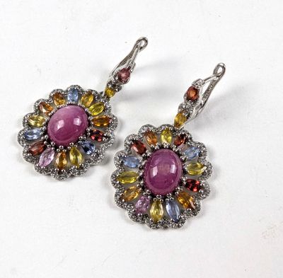 une paire de boucles d'oreilles ornées de pierres multicolores sur un fond blanc