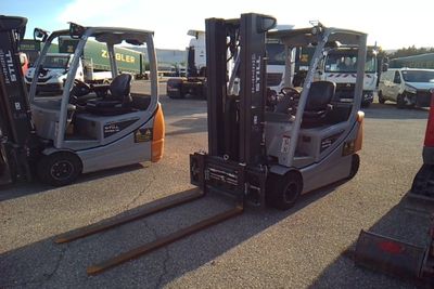 several forklifts are parked in a parking lot near other trucks