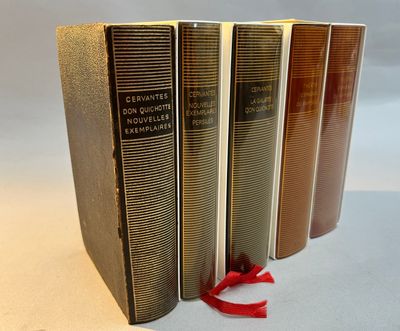 three books are lined up on a white surface with a red ribbon