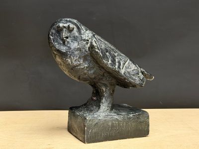 une photo représentant une statue de chouette posée sur une table en bois