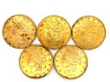 quatre pièces d'or sont disposées en ligne sur une surface blanche