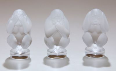 trois figurines en verre posées sur une surface blanche